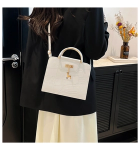 White faux-crocodile leather handbag with gold circular handle and deer charm detail