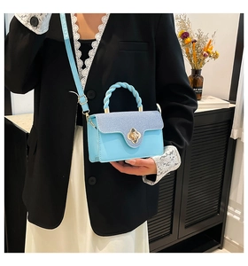 Detail of light blue crossbody bag with gold flower twist lock and braided handle on model