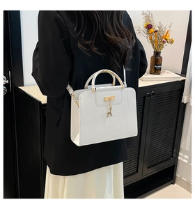 Detailed view of white crocodile pattern crossbody bag with golden deer charm