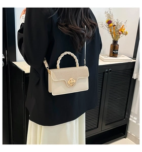 Model back view of cream crossbody bag with floral clasp and braided handle in home setting