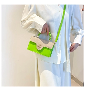 Detail of a green crossbody bag with woven flap and floral gold clasp on a model