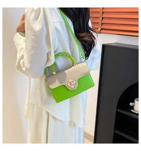 Close-up of bright green handbag featuring a golden flower clasp and woven handle