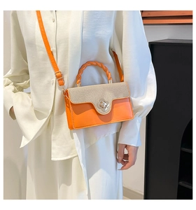 Macro shot of orange leather handbag featuring beige woven flap and flower twist lock