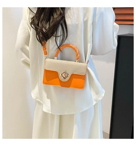 Detail of orange woven crossbody bag with floral metal buckle and spiral handle
