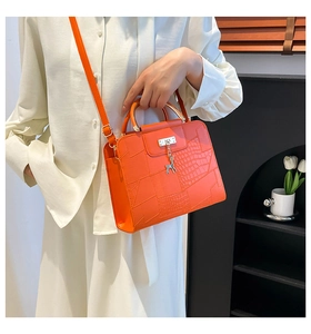 Close-up of orange crocodile pattern leather handbag with gold lock and deer charm details