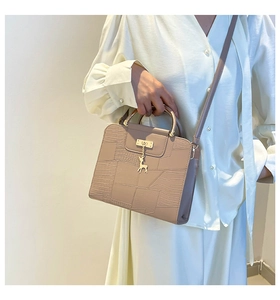 Detail of elegant crossbody bag with croc-embossed leather and golden deer charm