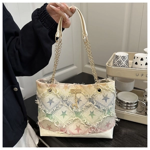Dettaglio della borsa tote in denim con motivo a stelle e ciondolo a cervo dorato