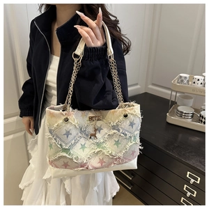 Detail of star-patterned denim tote bag with frayed edges and gold deer charm