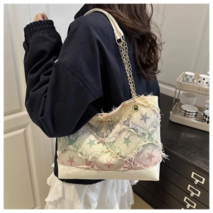 Dettaglio della borsa denim patchwork con motivi a stelle e tracolla a catena dorata
