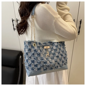 Dettaglio della borsa tote in denim a quadri blu e bianchi con frange e ciondolo a cervo
