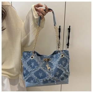 Dettaglio della borsa tote in denim con motivo a stelle, bordi a frange e catena oro