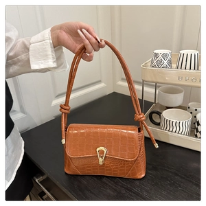 Détail du sac à bandoulière marron motif crocodile avec fermoir doré et sangle à nœud