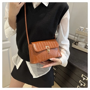 Détail d'un sac à main marron à motif crocodile avec une boucle en métal doré en U