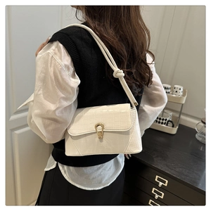 Detail of cream white crocodile texture handbag with golden horseshoe buckle and knotted strap