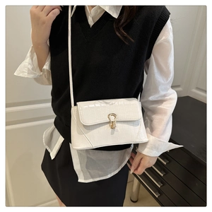 Détail d'un sac à bandoulière blanc effet crocodile avec boucle fer à cheval dorée et sangle