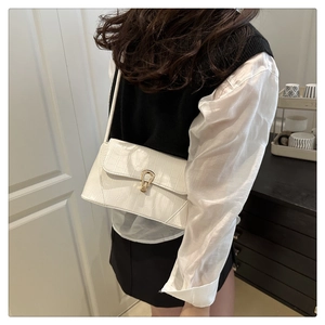 Détail d'un sac baguette blanc à motif crocodile avec fermoir fer à cheval doré