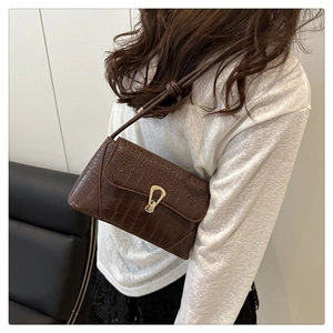 Detail of a dark brown crocodile texture bag with a luxury gold horseshoe buckle clasp