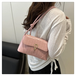 Pink crocodile-embossed baguette bag with gold horseshoe buckle worn by a model