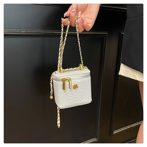 Detail der weißen Mini-Tasche mit Schlangenmuster, goldener Kamelie und Kettenriemen