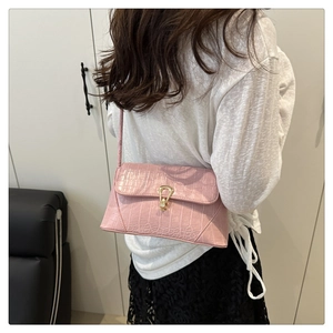 Détail du sac à bandoulière rose à motif crocodile avec une boucle en métal doré