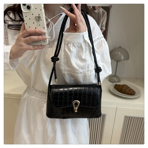 Detail of black crocodile texture PU leather handbag with gold horseshoe buckle clasp