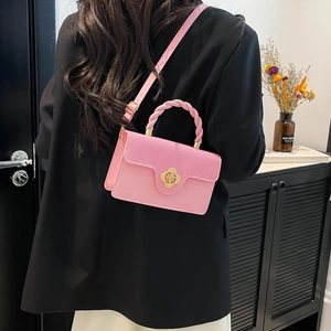 Pink crossbody square bag with woven handle and gold flower lock on a female model