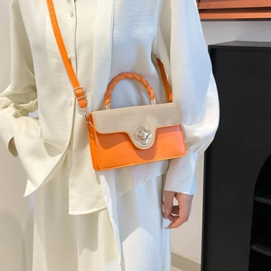 Chic orange and beige woven handbag with floral metal clasp shown on a white shirt