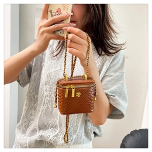 Detail der braunen Mini-Tasche mit Schlangenmuster, Kamelien-Logo und Kettenriemen