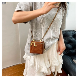 Detail der braunen Mini-Tasche mit Krokoprägung, Goldblumen-Anhänger und Kette