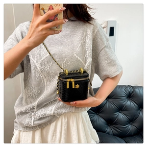 Detailaufnahme der schwarzen Mini-Box-Tasche mit Schlangenhautprägung und Goldblume