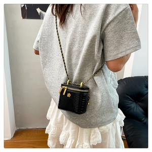 Rückansicht einer mini schwarzen Tasche mit Kroko-Prägung und goldener Kette an einem Model
