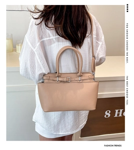 Chique beige draagtas met lychee-textuur en verstelbare riem gedragen door een model