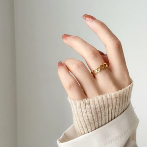Détail d'une bague dorée minimaliste au design élégant en forme de nids d'abeille