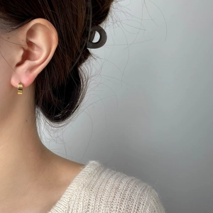Gros plan d'une large boucle d'oreille huggie en or poli portée à l'oreille