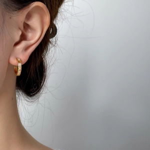 Gros plan de boucles d'oreilles créoles dorées en C avec zircons carrés verticaux