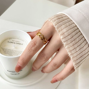 Bague ajourée en forme de cœur doré portée à l'index dans un décor de style de vie chaleureux