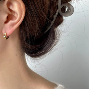 Gros plan d'une femme portant une boucle d'oreille créole dorée en C de style moderne