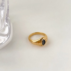 Détail d'une bague chevalière vintage dorée avec une pierre ovale noire polie au centre
