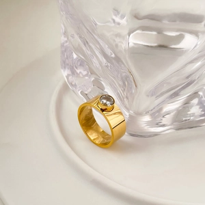 Vue macro d'une bague large dorée avec zircone et finition polie à effet miroir