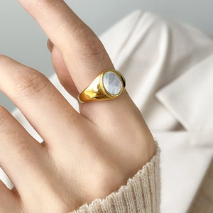 Gros plan d'une bague chevalière vintage dorée avec une incrustation ovale en nacre