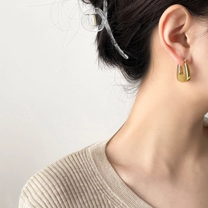 Close-up of minimalist U-shaped gold earrings on a model for an elegant lifestyle look