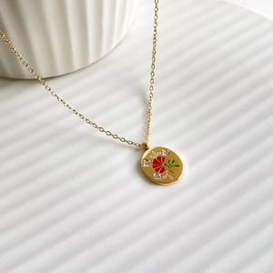 Macro view of gold-plated oval pendant with floral enamel design and star details