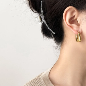Polished gold U-shaped hoop earrings paired with a large transparent hair claw clip