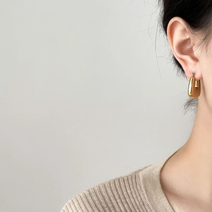 Minimalist gold U-shaped hoop earrings with polished finish shown on a model