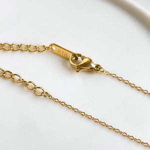 Macro shot of gold plated necklace lobster clasp with K18 engraved metal tag and O-chain