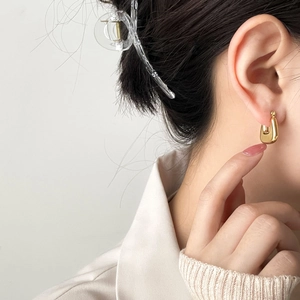 Elegant gold U-shaped hoop earrings with minimalist geometric design on female model
