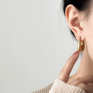 Close-up of elegant gold U-shaped hoop earrings on model for a minimalist fashion look