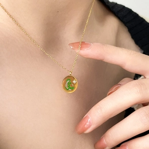 Detailed shot of gold coin pendant with green enamel snake design and zircon star inlay