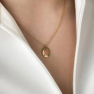 Artistic gold-plated titanium necklace with pink enamel floral oval pendant on a model