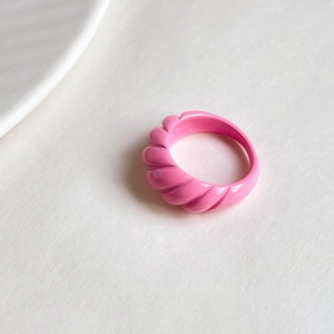 Detailed top view of a pink croissant-shaped open ring with elegant spiral textures